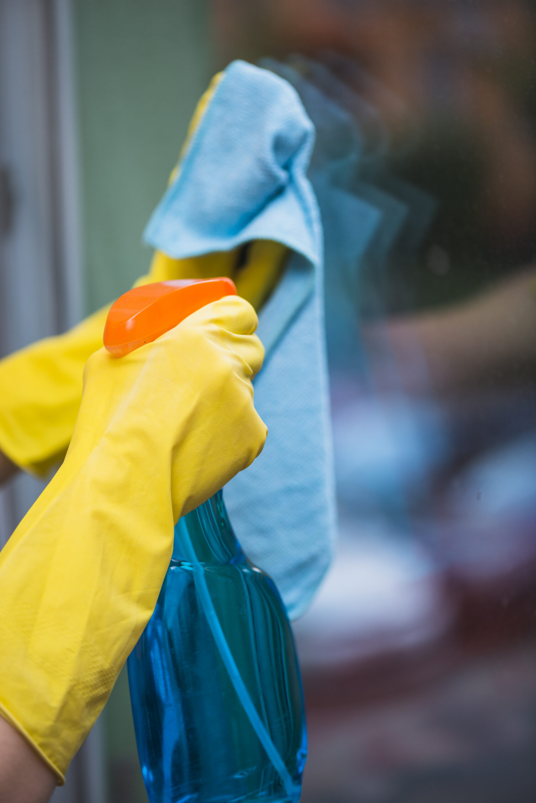 housekeeper spraying detergent with spray bottle glass window